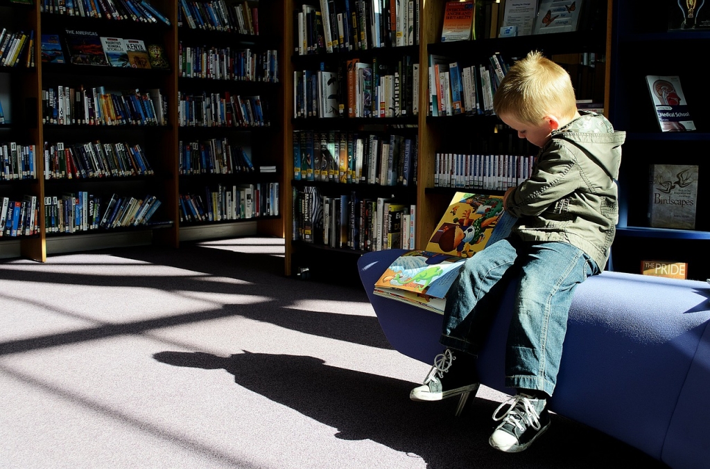Malo dijete čita knjige o marketingu u knjižnici